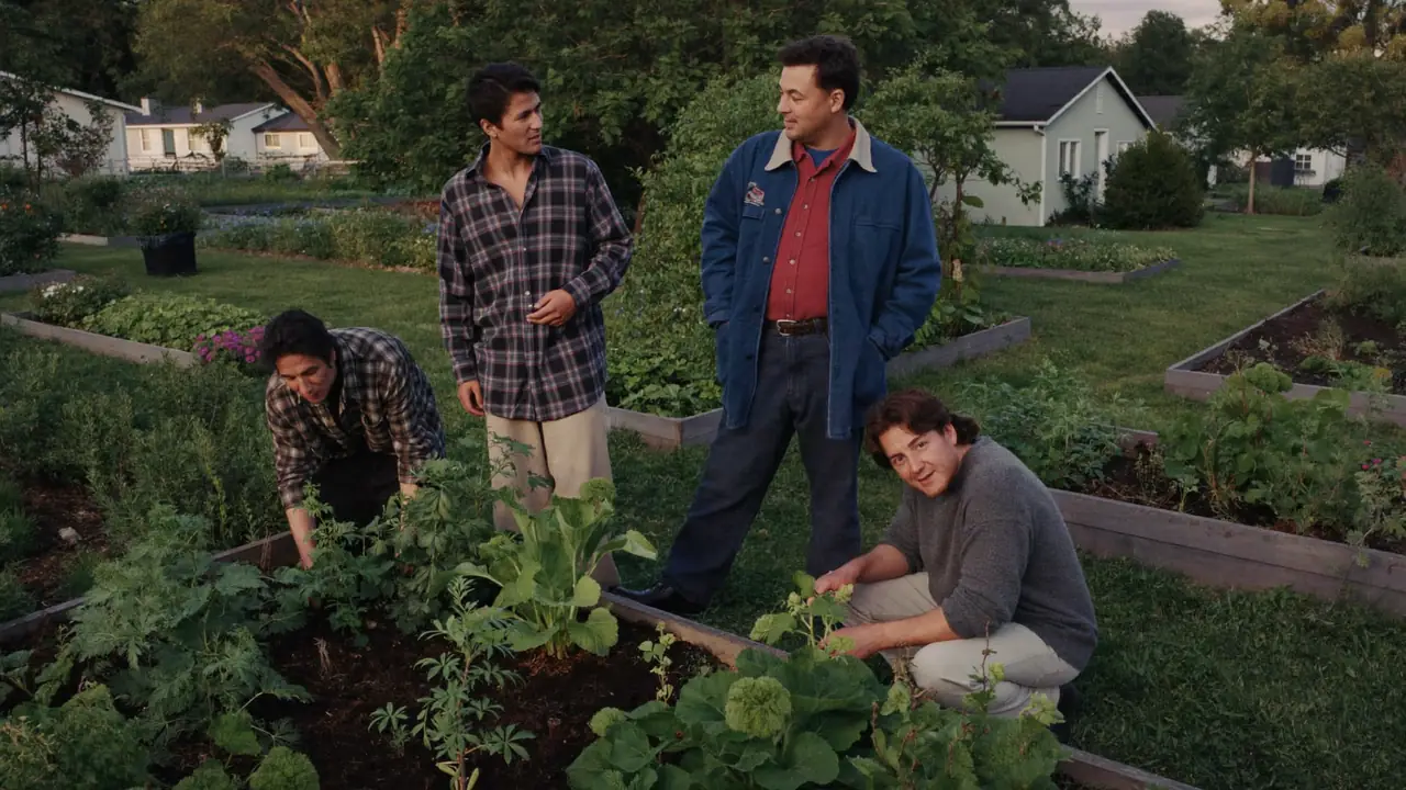Four adults of different ages tending raised beds together in a neighborhood community garden.
