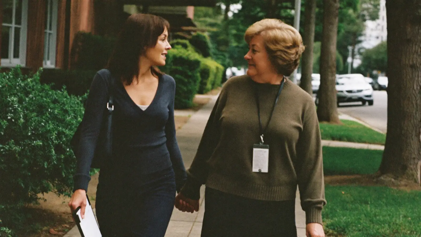 A support professional and the adult she supports walking together and talking on a residential street.