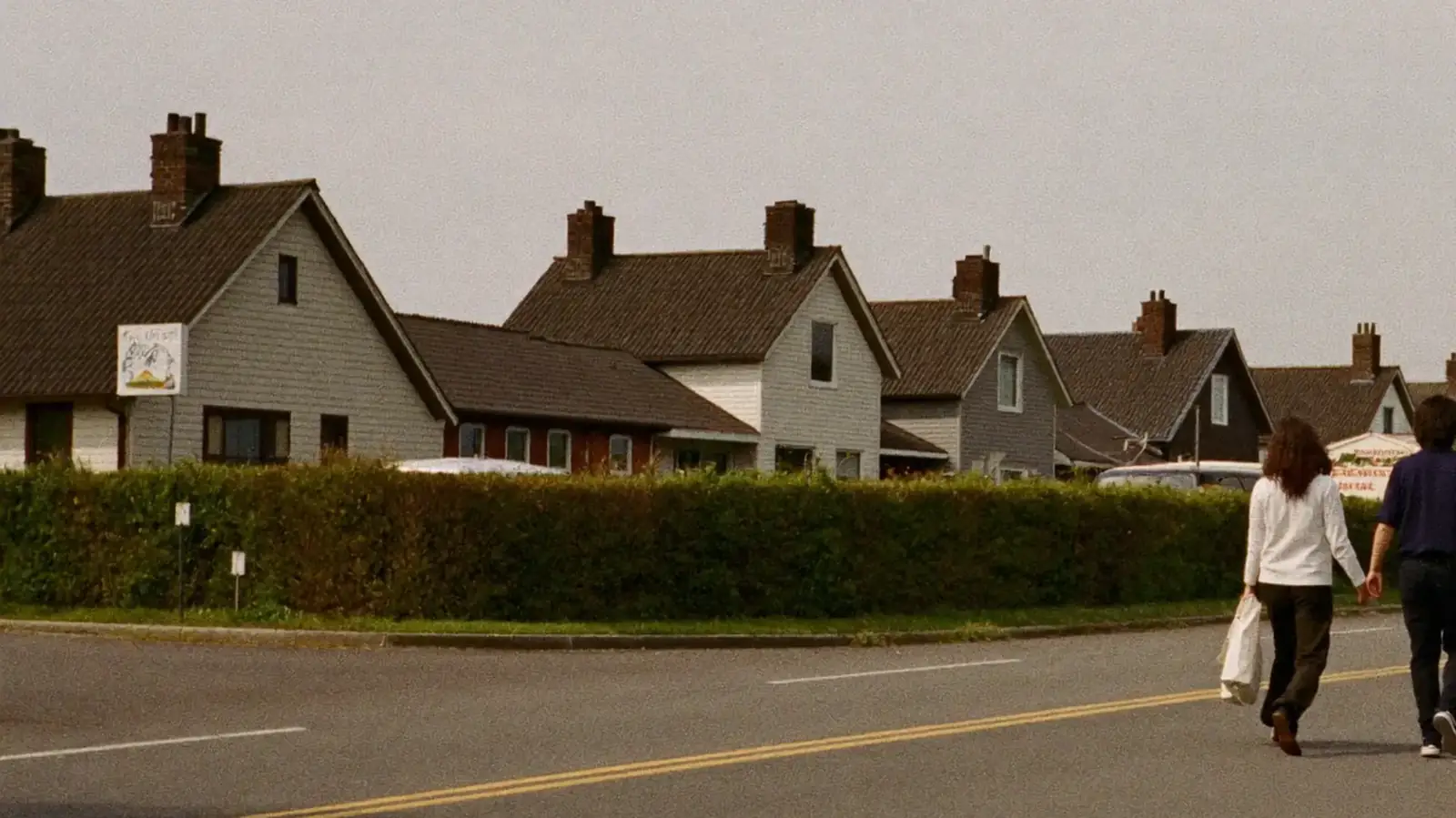 Two adults walking together along a quiet residential street.