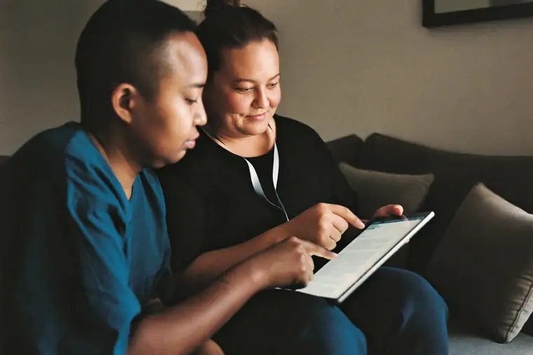Two adults sitting together on a sofa looking at a tablet.
