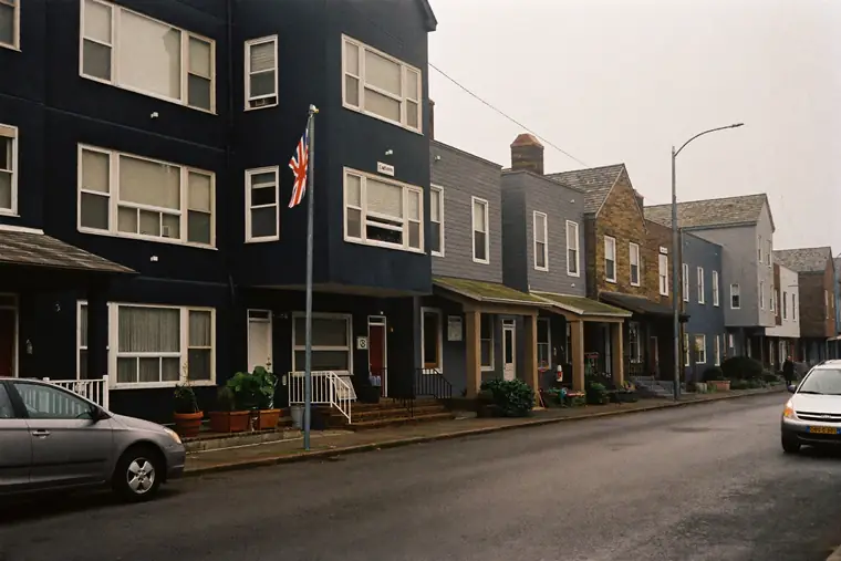 A row of modest apartment buildings and houses on an ordinary residential street.