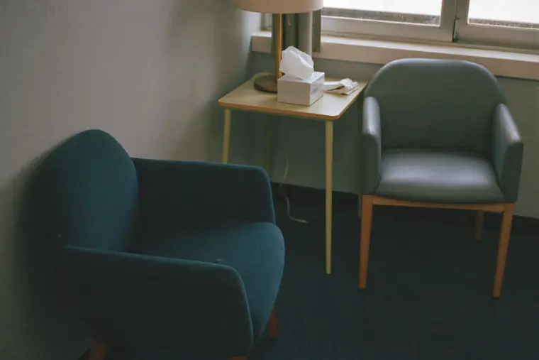 Two empty chairs angled toward each other in a quiet, softly lit room.